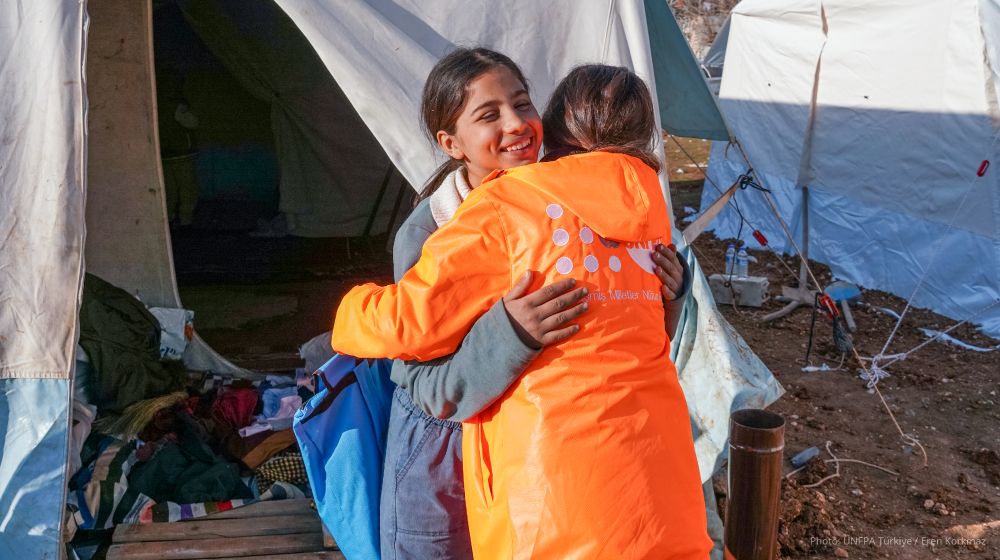 Bir çadır kentinte bir UNFPA çalışanına sarılan bir kız