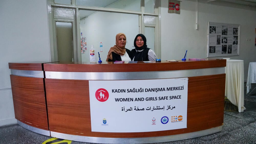 Two women are seen posing behind the information desk at UNFPA headquarters.