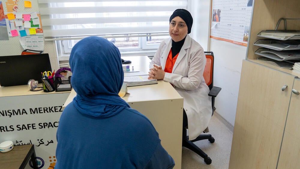 Two women are seen in the photo with one of them face the other in the direction of the camera. She is wearing health personnel clothes and providing counseling services to the other woman.