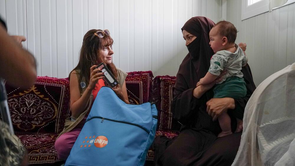 Marziye, who was affected from the earthquake, is receiving a hygiene kit in the container city she lives in.