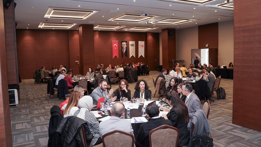 Participants of the event are seated in round tables and doing group work.