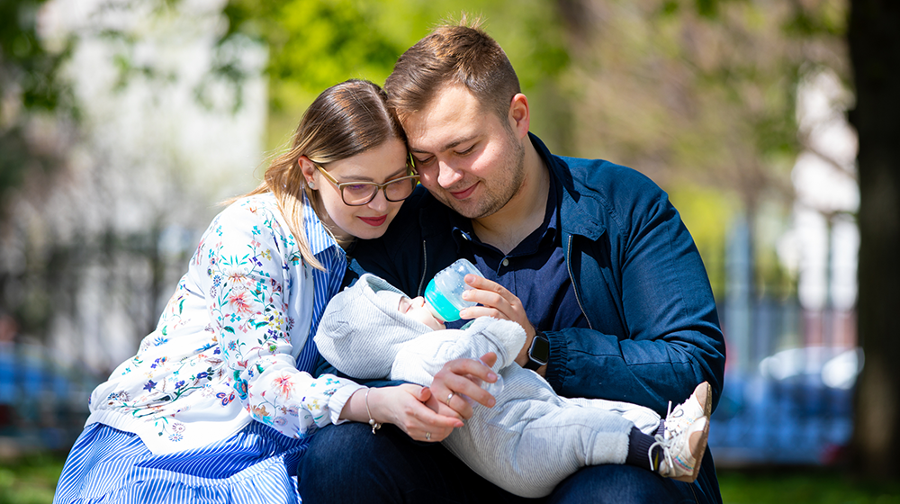 A father and a mother are caressing their baby. 