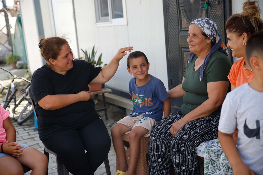 Gönül, her family and her relatives are spending time on the divan outside the containers. 