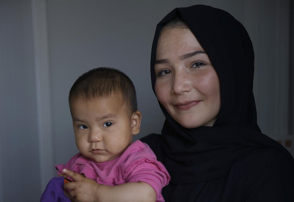 Sara holds her daughter Rina in her arms and tells about the training programs organized by UNFPA in the container city.