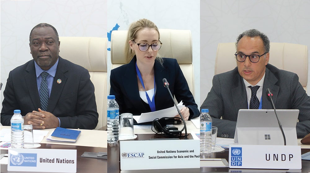 Three UN officials are seated at a conference table, representing different UN bodies during a formal meeting.
