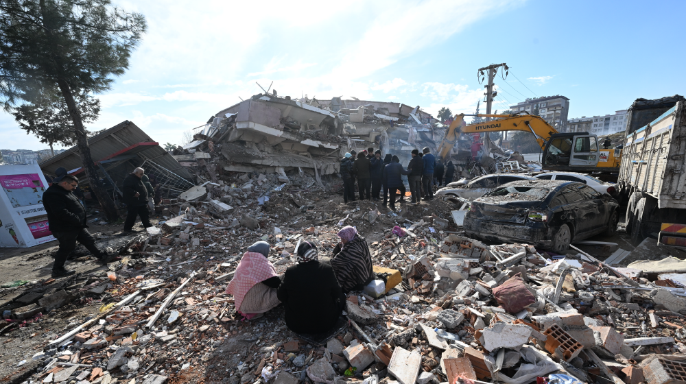 Women sitting on the rubble of a collapsed building
