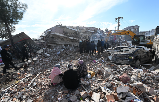 Yıkılmış bir binanın enkazında oturan kadınlar.