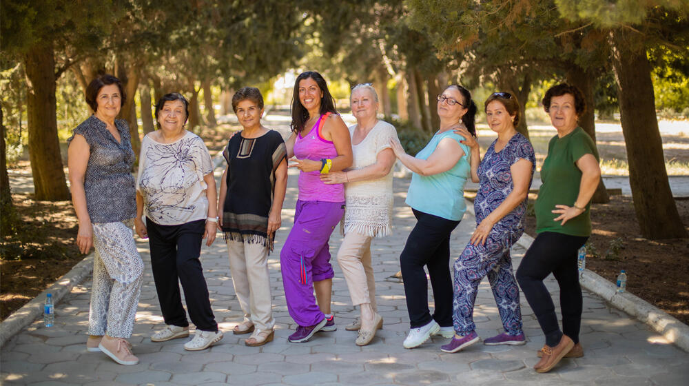 Eight women stand in the pavement surrounded by trees.