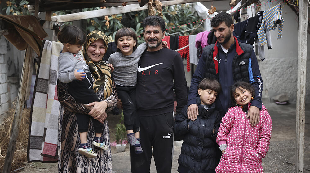 Yedi kişilik bir aile sokakta gülümsüyor.