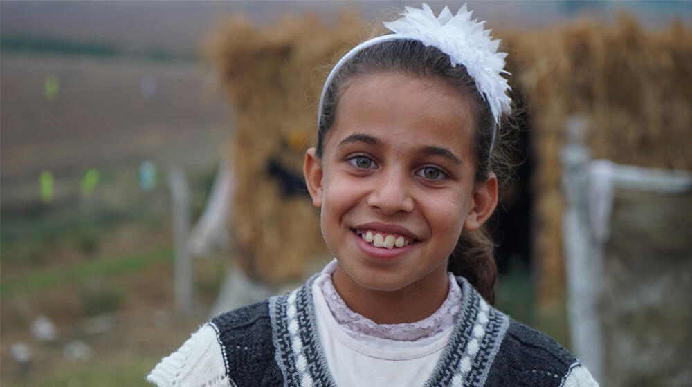 A little girl smiles in a rural settlement.