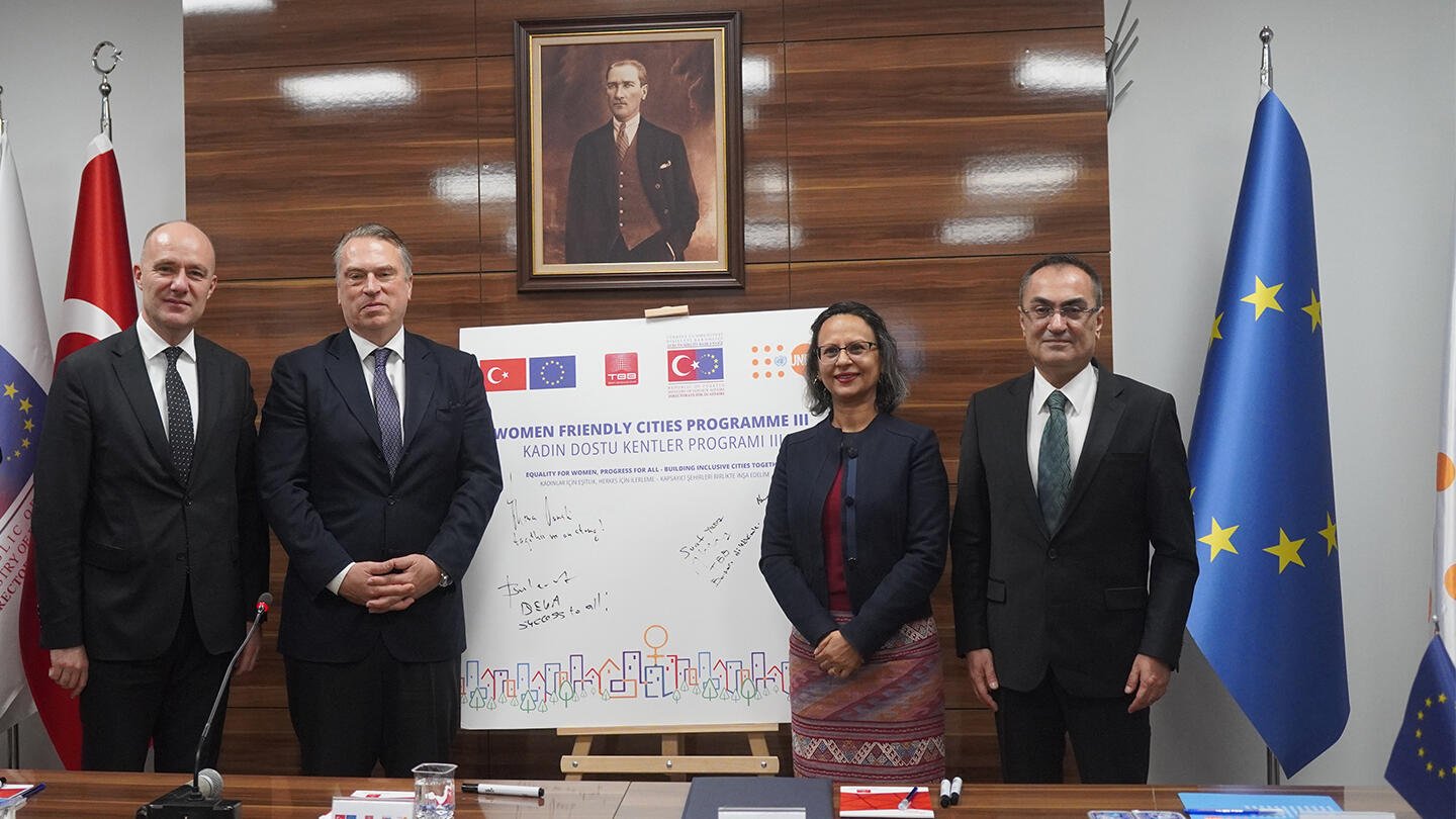 Four people are next to a board that they signed, symbolizing the launch of a joint programme. 