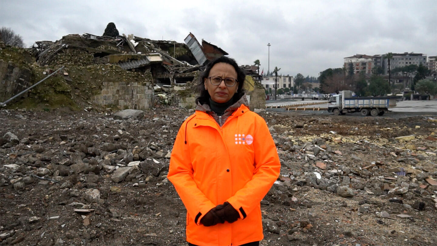 Mariam A. Khan is  seen and behind her is a debris.